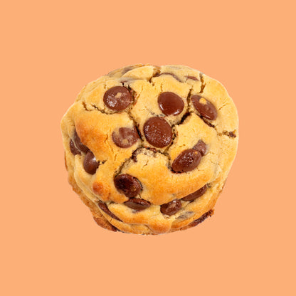 Cookie artisanal aux grosses pépites de chocolat au lait Callebaut, doré et moelleux, vu de dessus sur fond beige orangé chaud, texture craquelée et généreuse